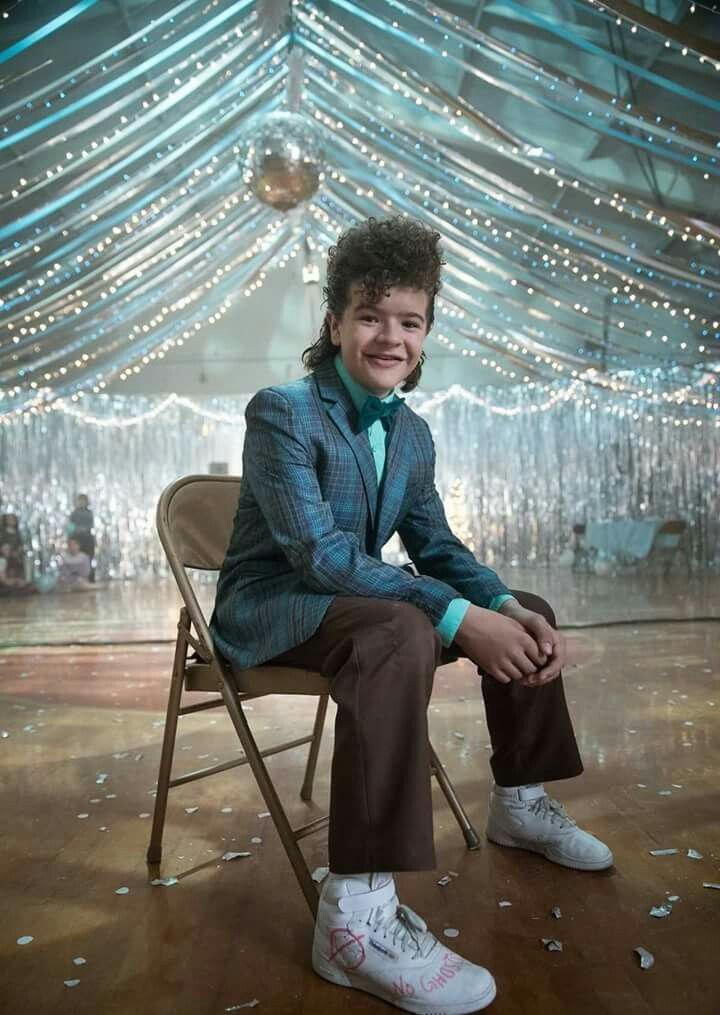 a young man sitting on top of a chair in front of a ceiling covered with lights