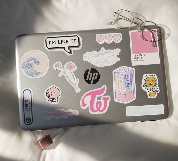 a laptop covered in stickers on top of a bed