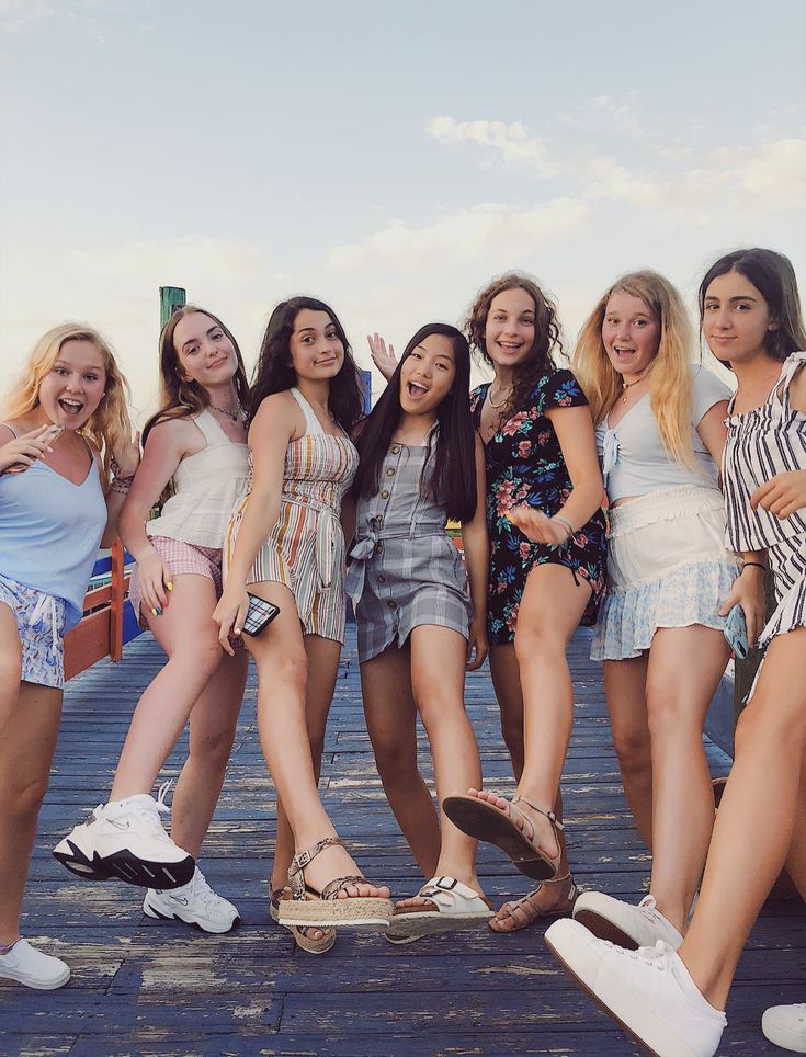 a group of young women standing next to each other on a wooden pier with their feet up in the air