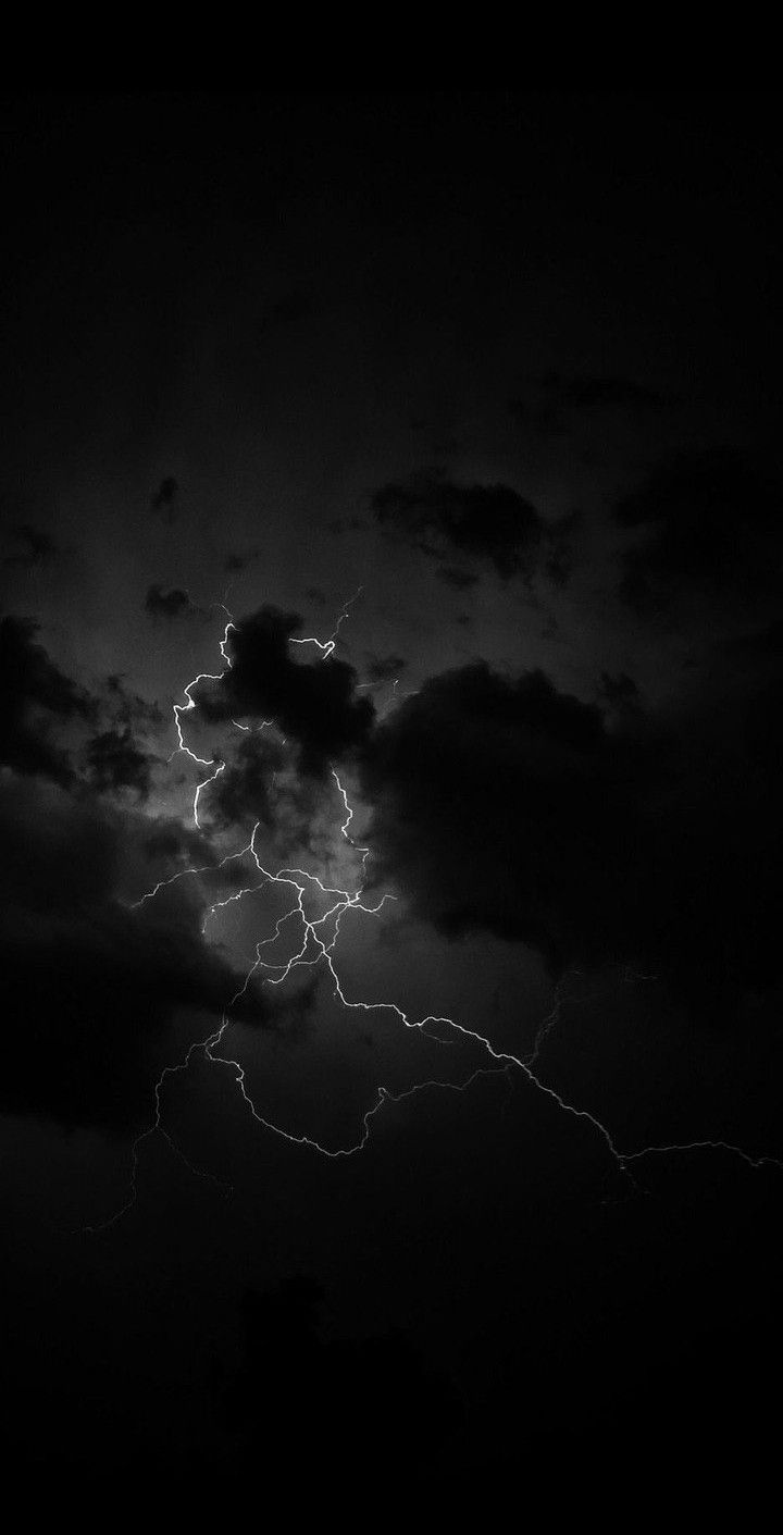 a black and white photo of lightning in the night sky with dark clouds behind it