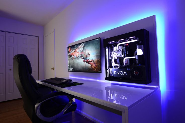 a desk with a computer monitor on top of it next to a wall mounted gaming system