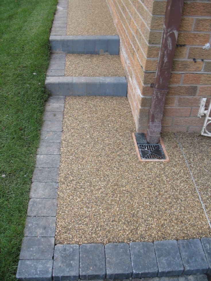 a brick wall and steps leading up to the side of a house with grass in front