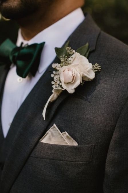 a man in a suit with a flower on his lapel and a green bow tie