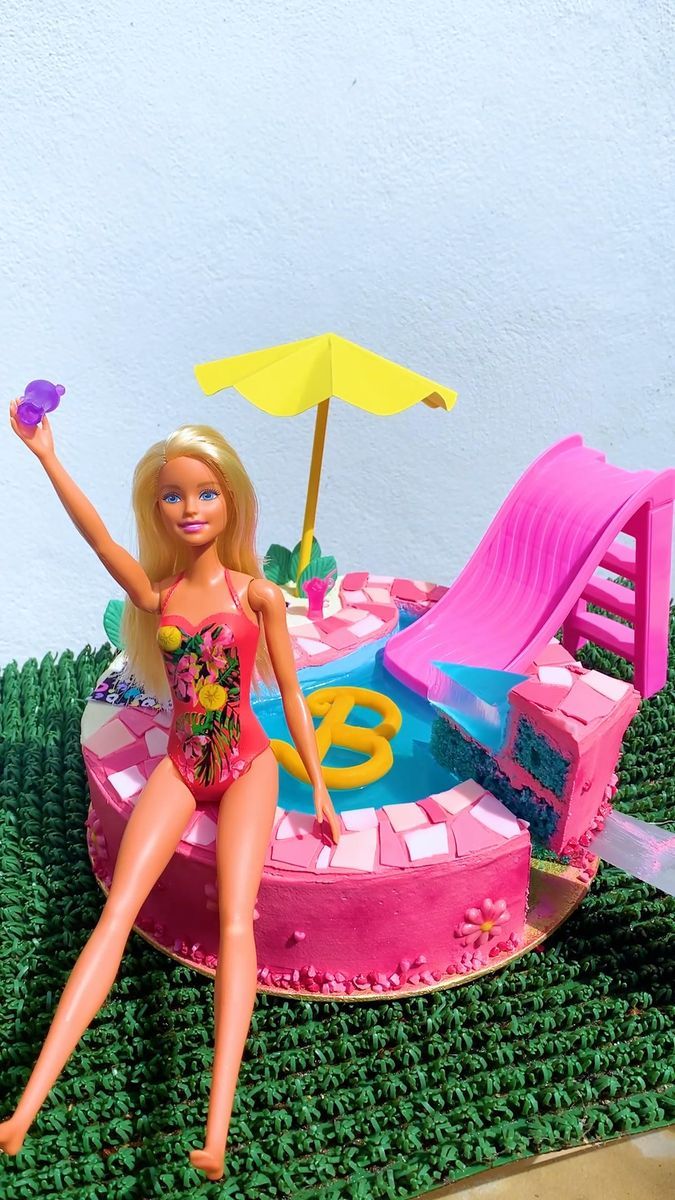 a barbie doll sitting on top of a pink and green pool with a beach umbrella