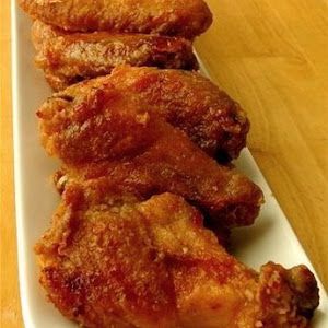 fried chicken on a white plate sitting on a wooden table