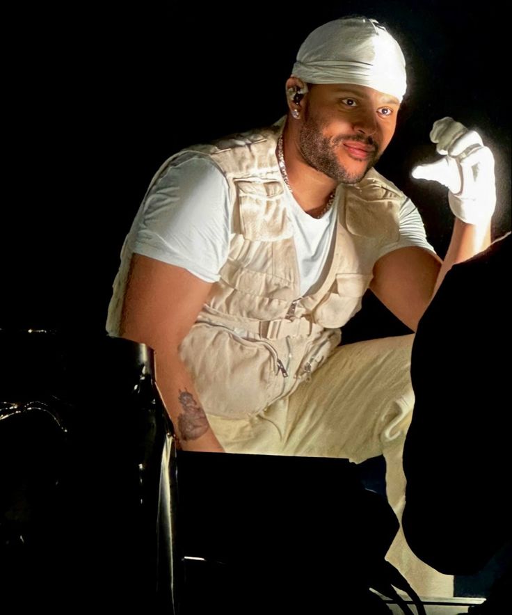 a man sitting on top of a chair in front of a laptop computer wearing a white hat