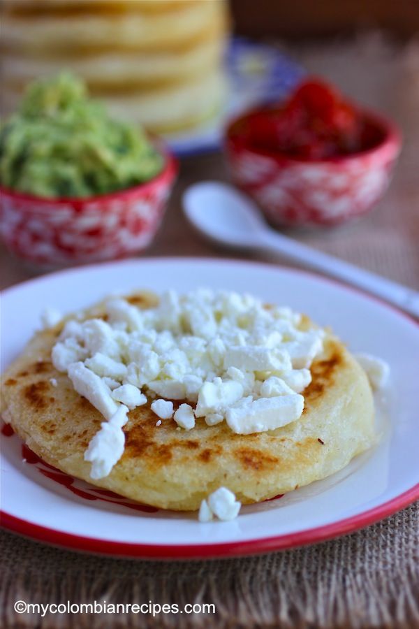 some food is on a white plate with red trim around it and bowls of guacamole in the background