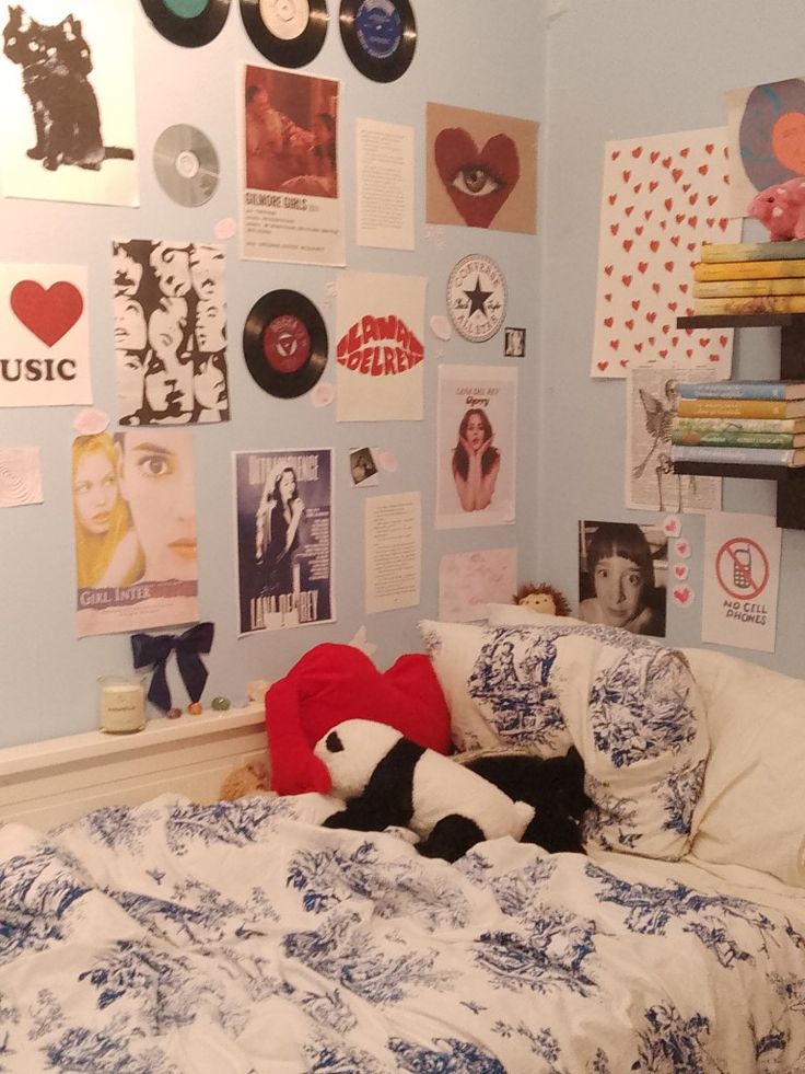 there is a bed with many pictures on the wall and a teddy bear laying on it