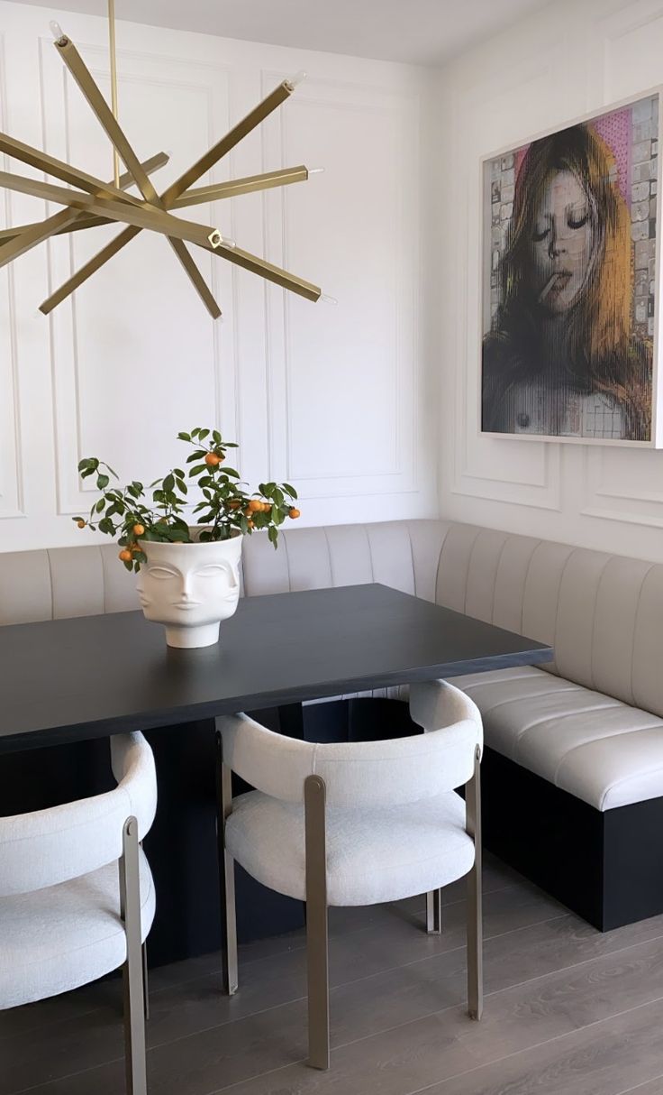 a dining room table with two white chairs and a plant in the center on top