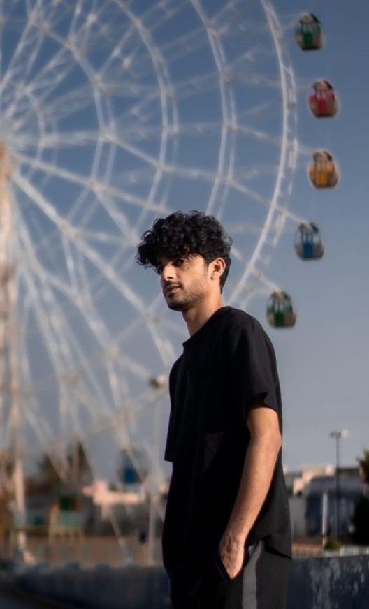 a man standing in front of a ferris wheel