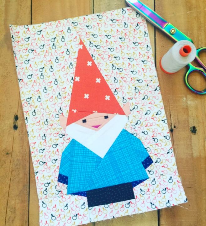 a piece of paper with an image of a gnome on it next to scissors and thread