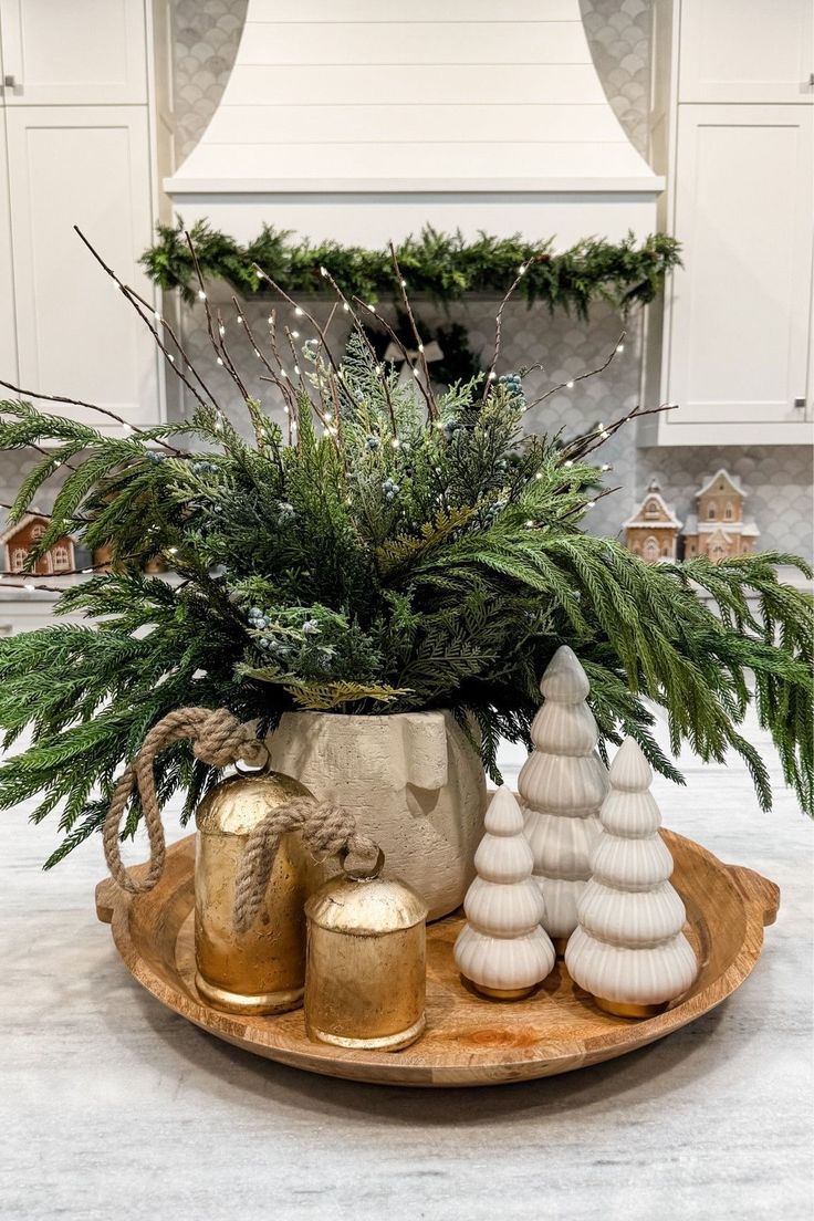 a potted plant sitting on top of a wooden platter filled with christmas decorations