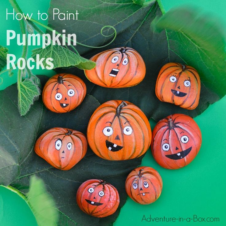 pumpkins with faces painted on them sitting next to leaves