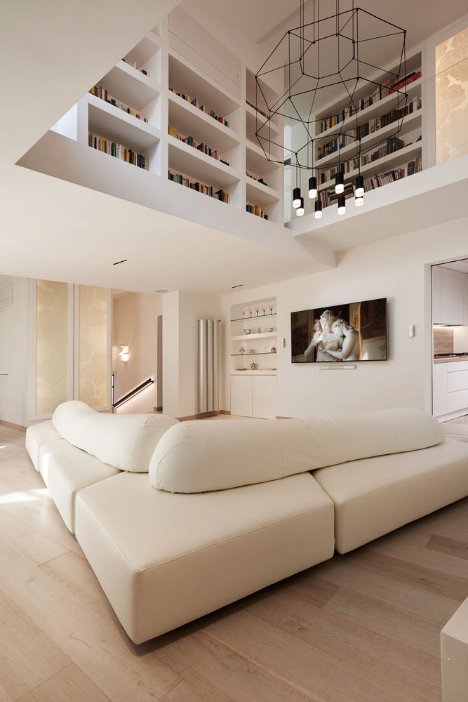 a large white couch sitting in a living room next to a book shelf filled with books