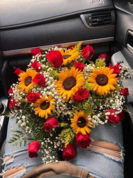 a bouquet of sunflowers and red roses in someone's jeans sitting in their car