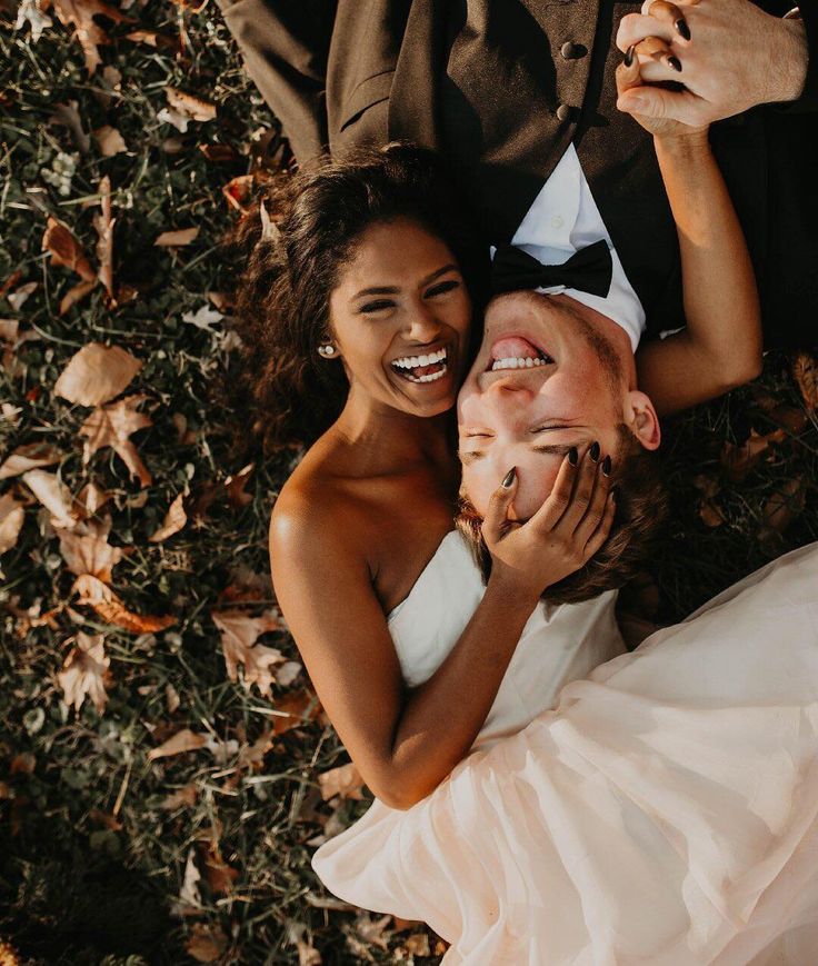 a man and woman laying on the ground with their hands around each other's heads