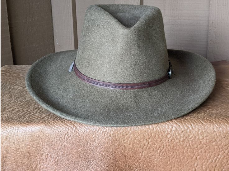 This 100% wool felt fedora is classically styled. Ready for your outdoor adventure! Perfect styling for a man or a woman. Simple leather hatband that is finished with a replicated Buffalo Nickel Concho. It has a stampede string to keep your hat on your head when the wind kicks up. Water resistant and crushable. The brim is 3.5" and the crown is 4.5" This hat ships within 2 - 3 days. Introduced in 1913, the Buffalo Nickel was an early hit with collectors and a major circulation workhorse through Country Style Hat Bands With Flat Brim For Travel, Country Style Flat Brim Hat Bands For Travel, Country Style Felt Hat With Flat Brim For Travel, Country Style Flat Brim Felt Hat For Travel, Country Style Travel Felt Hat With Flat Brim, Western Style Fedora Felt Hat For Travel, Rustic Felt Hat With Flat Brim For Outdoor, Western Felt Hat With Curved Brim For Travel, Western Style Felt Hat With Curved Brim For Travel