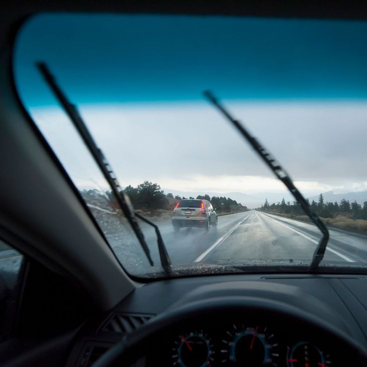 a car driving down the road in front of another car on a highway with trees