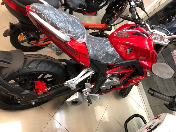 a red motorcycle parked in a showroom next to other motorcycles