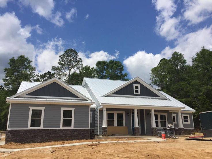 a house being built in the middle of a field with lots of dirt and trees