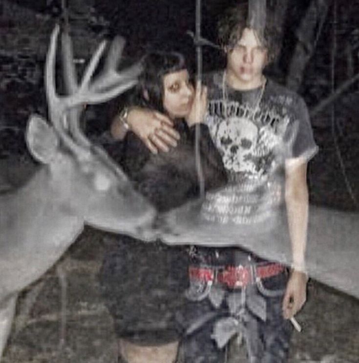 two people standing next to each other near a deer