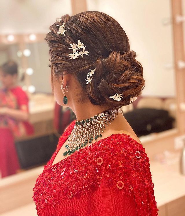 a woman in a red dress is looking at herself in the mirror with her hair pulled back