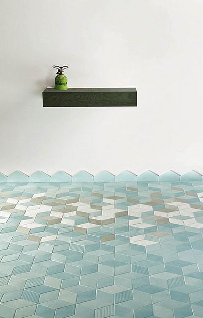 a green vase sitting on top of a shelf in front of a wall covered in blue tiles