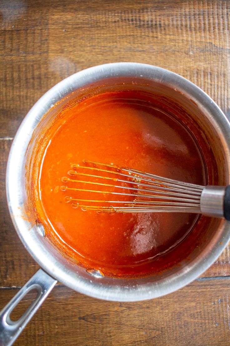 the sauce is being whisked with a whisk in a silver pot