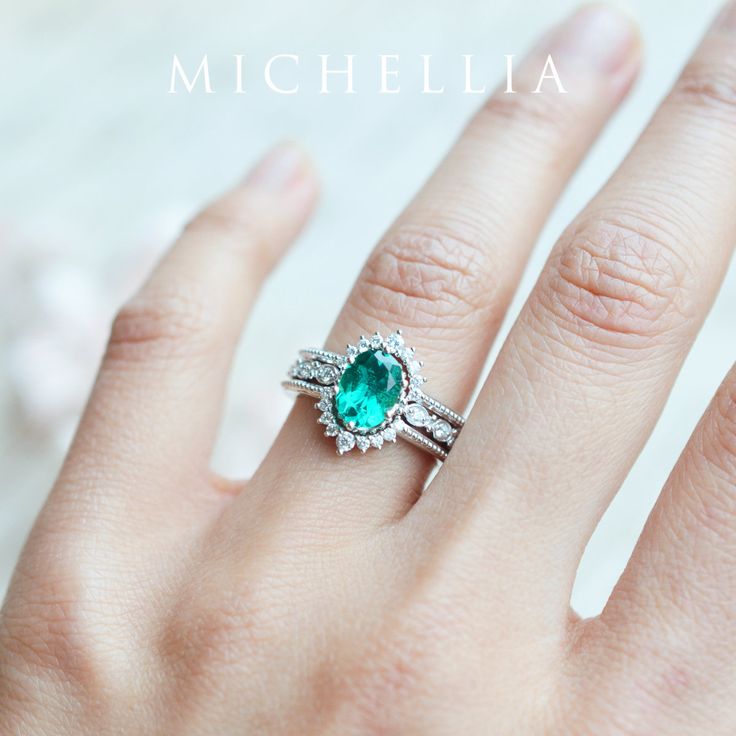 a close up of a person's hand wearing a ring with an emerald stone