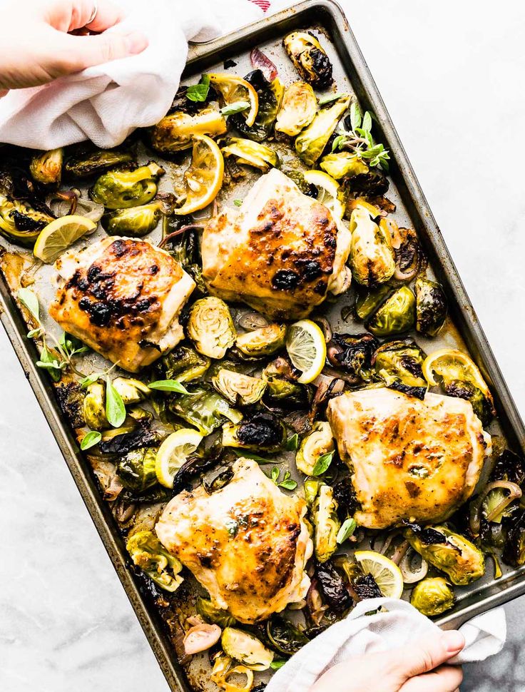 chicken and brussels sprouts in a baking pan with a napkin on the side