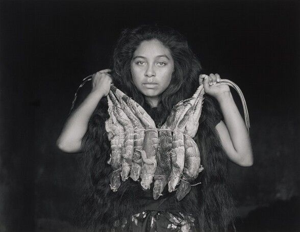 a black and white photo of a woman holding fish in front of her face with both hands