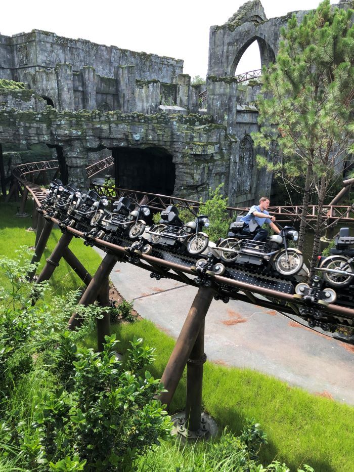 a man riding on the back of a motorcycle across a wooden bridge over green grass