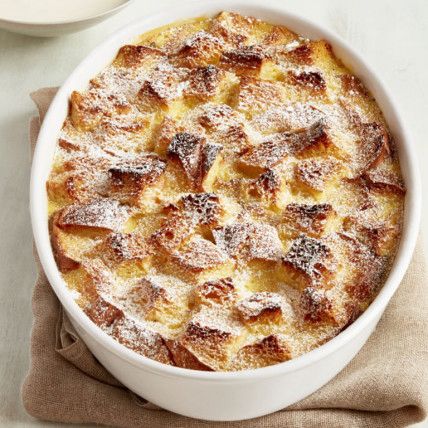 a casserole with powdered sugar on top in a white dish next to a cup of coffee