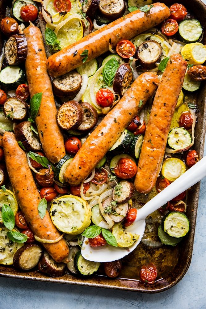 sausages and vegetables in a baking dish with a spatula