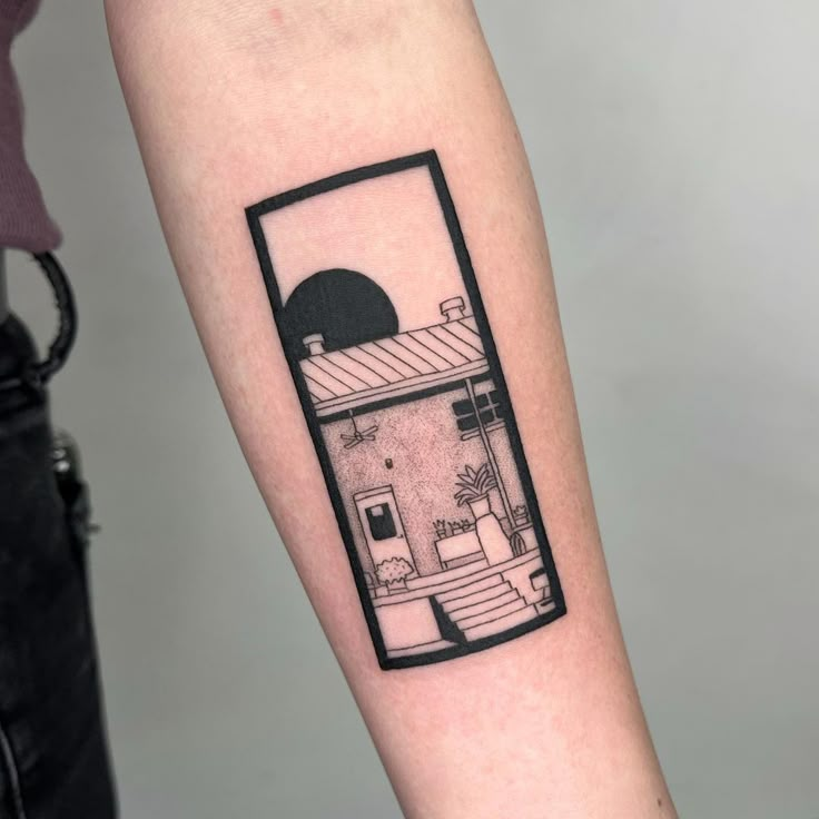 a black and white photo of a small house tattoo on the right arm, with stairs leading up to it