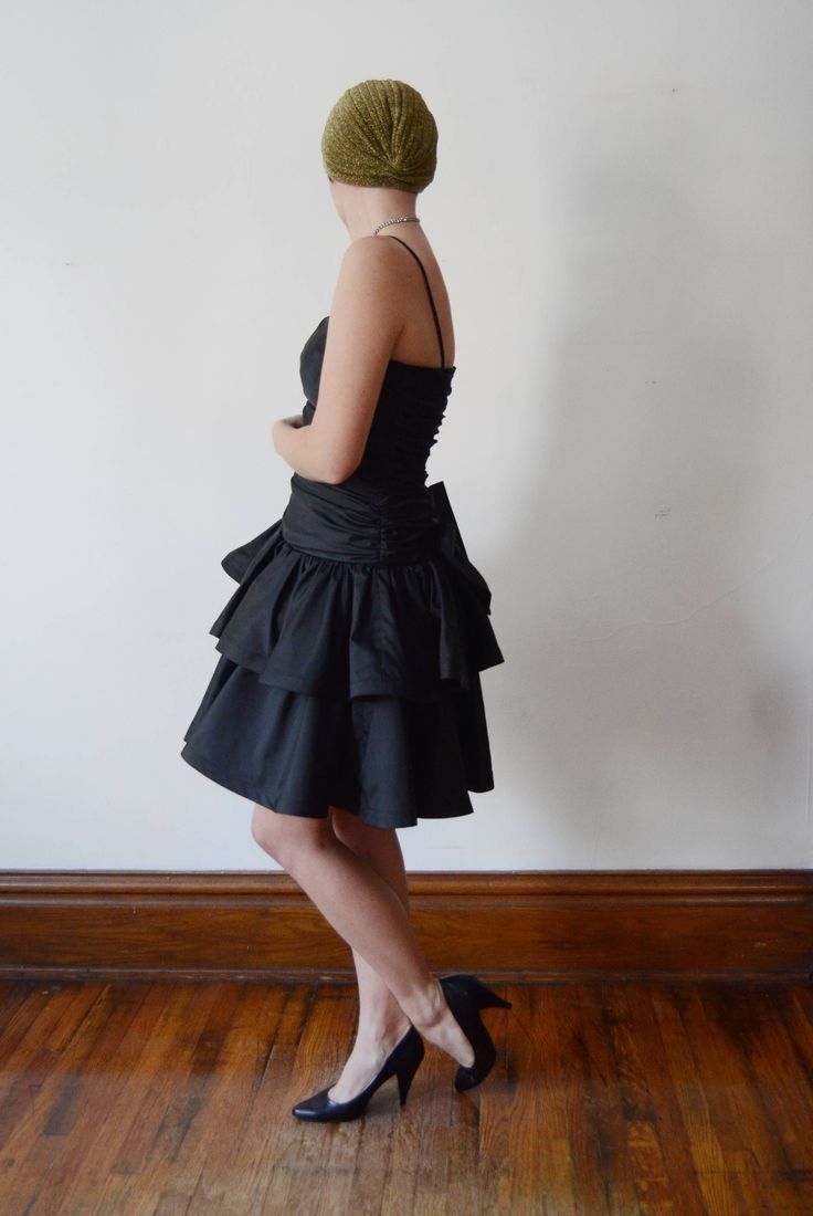 "Description: Black party dress with a drop waist and ruffled skirt. zips up the back and has a large decorative bow. Some tulle under the skirt for fullness. Bodice has boning up the sides. Measurements of garment, allow space for fit. Bust: 32\" some some gathers for cup space. Shown on 36\" and it was way too snug. Waist: 28\" Hips: Open Length: 37\" Skirt length: 15\" I take my measurements flat, and double for circumference. Tag: No brand, just an ILGWU label. Fabric: Polyester Condition: E Black Party Dress, Under The Skirt, Black Party Dresses, Ruffled Skirt, Grand Rapids Mi, Black Party, Grand Rapids, Black Ruffle, Drop Waist