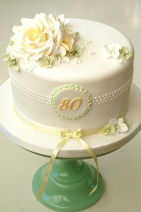 there is a white cake with flowers on the top and an 80 sign on the bottom