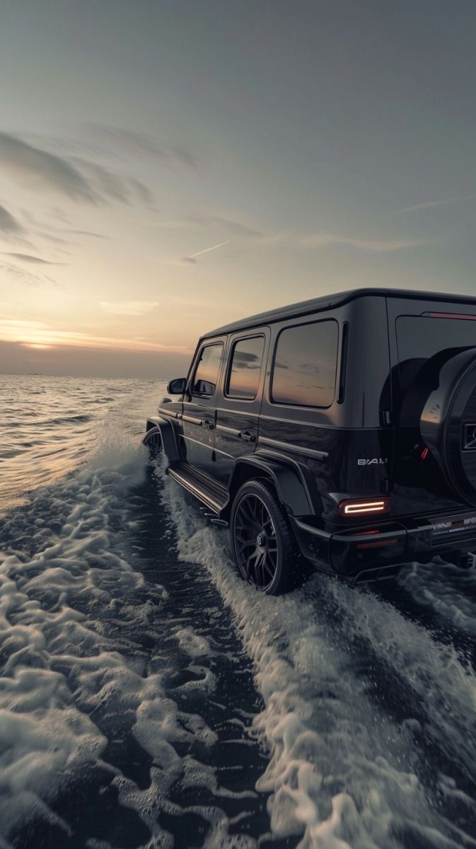 the mercedes benz g - class is driving on the water at sunset or dawn with clouds in the sky