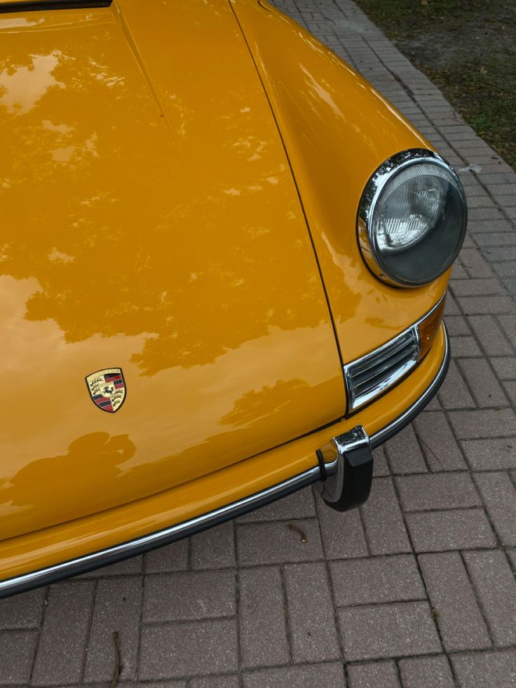 the front end of an old yellow sports car