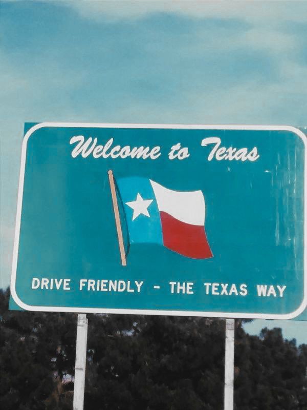 a welcome to texas sign with trees in the background