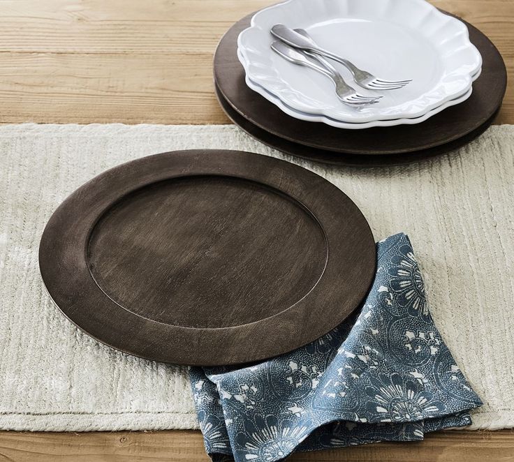 a place setting with plates, napkins and silverware on a wooden table top