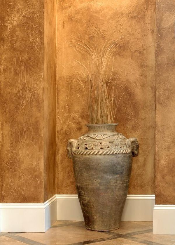 a large vase sitting on top of a tiled floor next to a wall with peeling paint