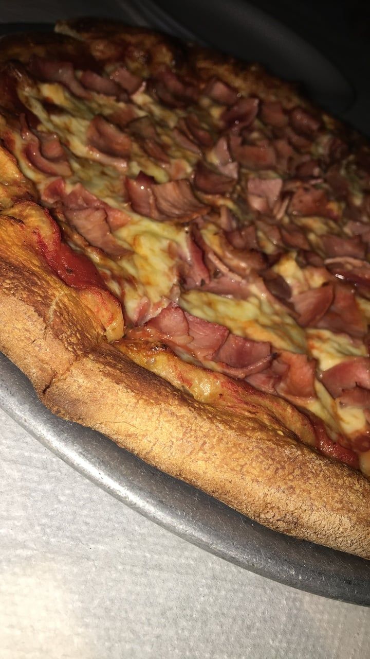 a pizza sitting on top of a metal pan covered in cheese and meat toppings