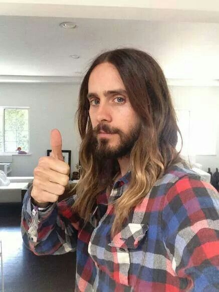 a man with long hair giving the thumbs up