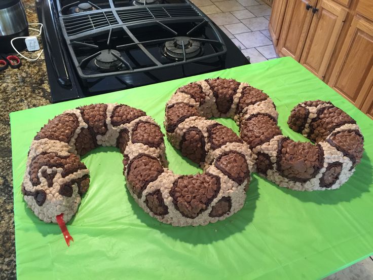 a cake shaped like a snake on top of a green tablecloth in the kitchen