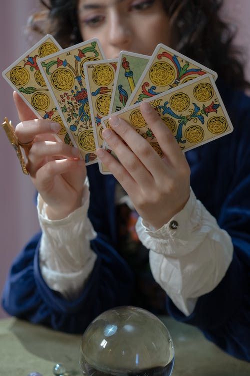 a woman sitting at a table holding four playing cards