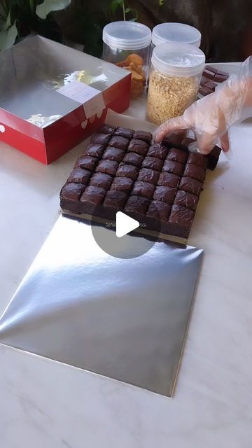 a person is cutting up some brownies on a white table with other food items