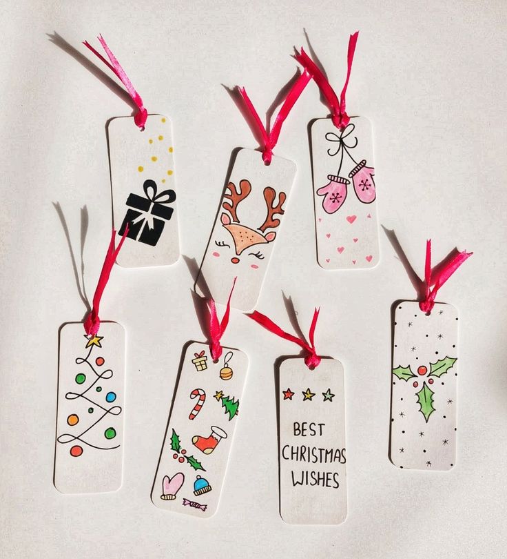 six tags with christmas designs on them hanging from red ribbon bows and ribbons in front of white background