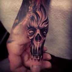 a person with a tattoo on their arm holding up a hand that has a skull tattooed on it