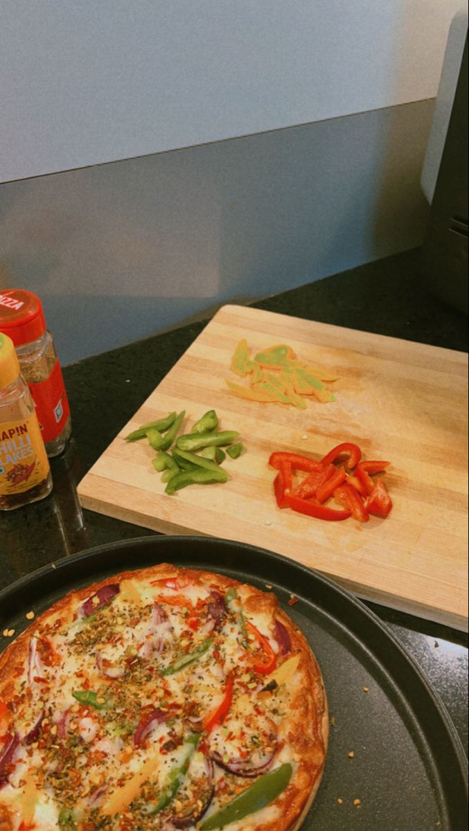 a pizza sitting on top of a pan next to a cutting board and seasoning bottle